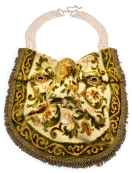 Photo d'une œuvre-bijou: un collier dont le pendentif ressemble à un visage dans un morceau de tapis, monté sur un collier de perles à 4 rangées.